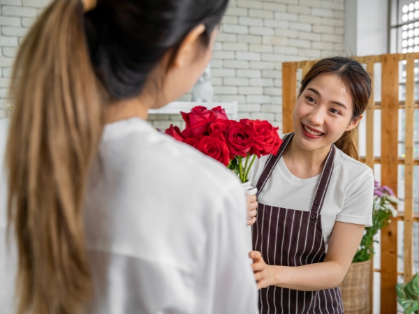 woman giving flowers at La Rosa Flower Shop anniversary surprise
